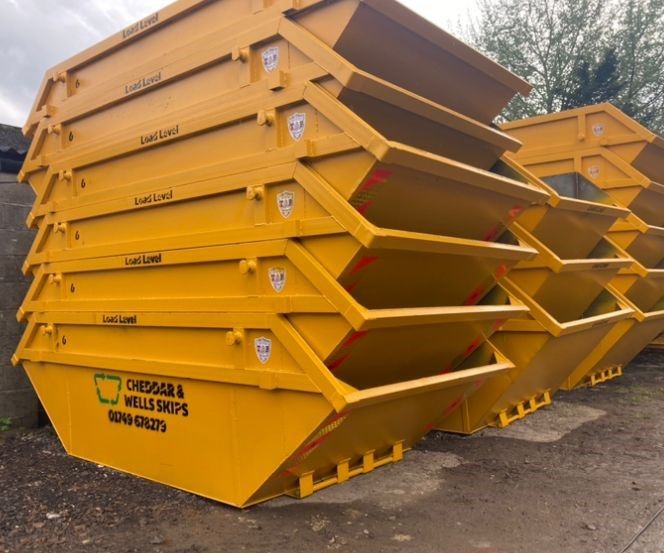 A stack of yellow Cheddar & Wells skips in the yard